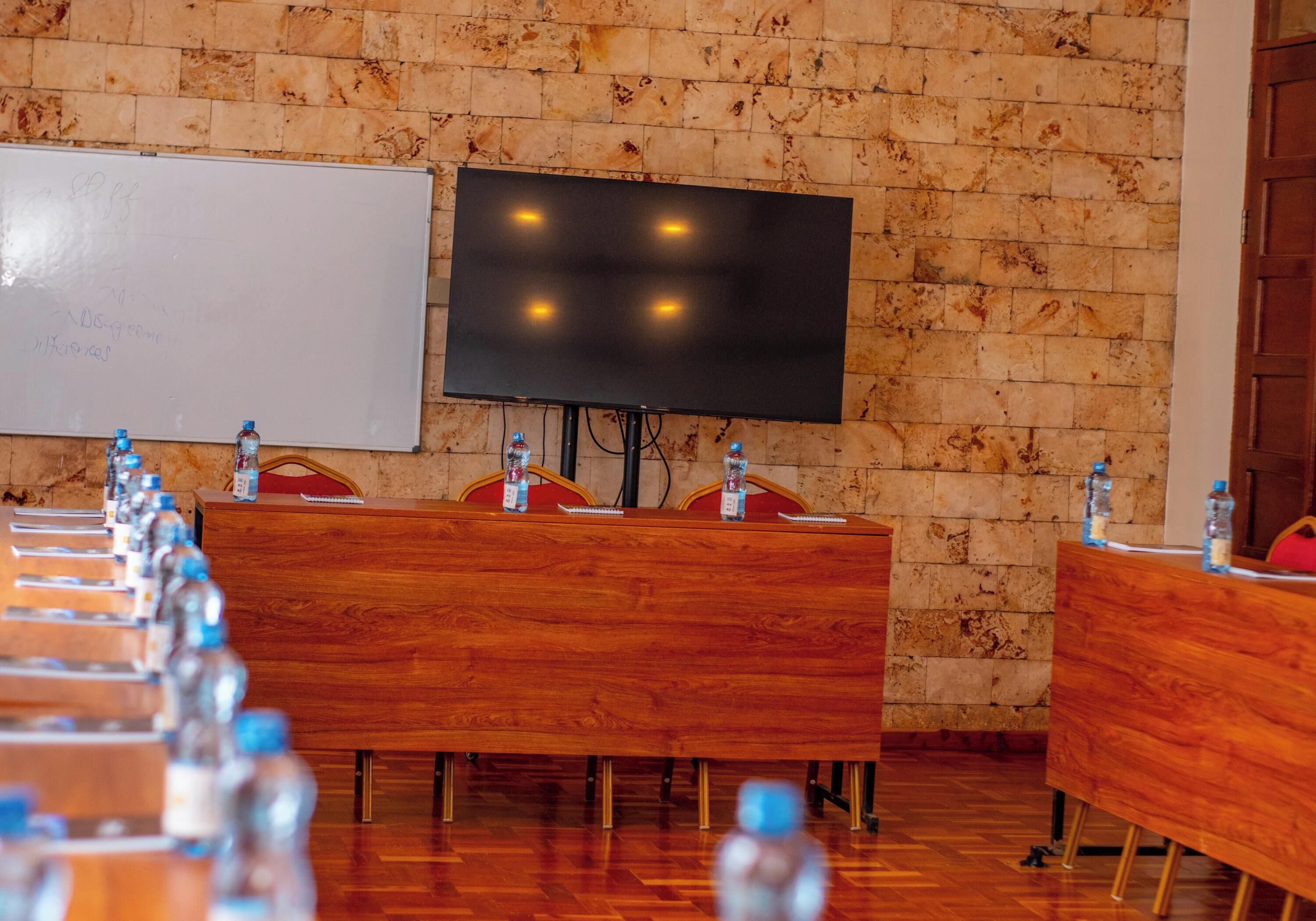 A conference room with wooden tables, a whiteboard, and a large flat-screen TV.