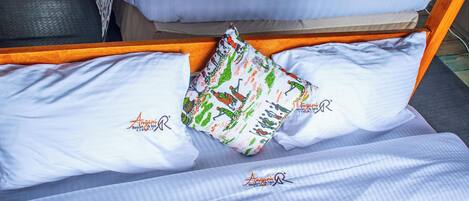A bed with white linens and a colorful pillow.