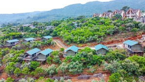 Um resort numa encosta com várias acomodações em estilo de bangalô, cada uma com varanda e rodeada por vegetação exuberante.