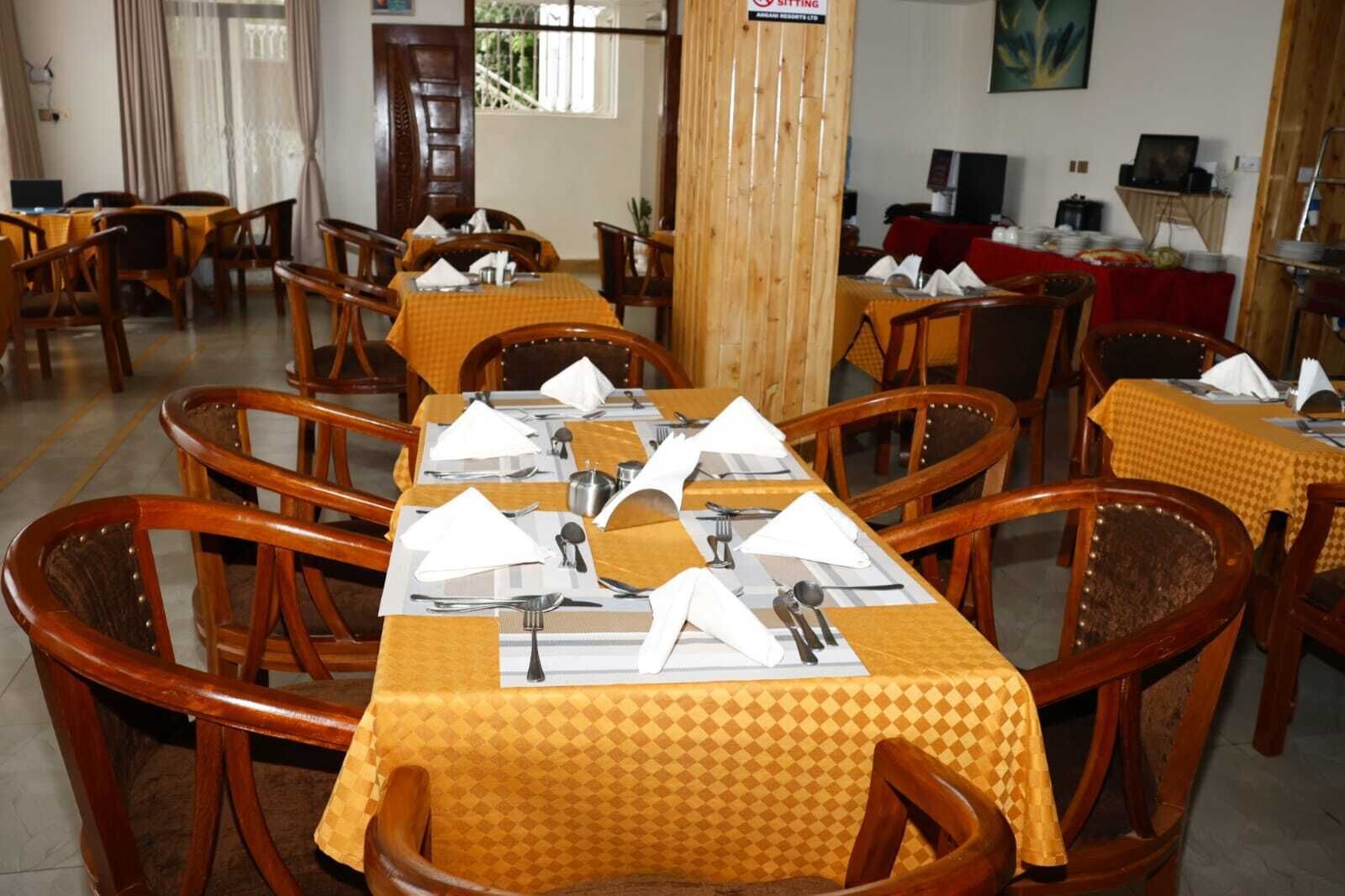Comedor con varias mesas dispuestas para el servicio, sillas de madera y mantel rojo.