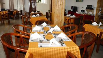 Comedor con varias mesas dispuestas para el servicio, sillas de madera y mantel rojo.