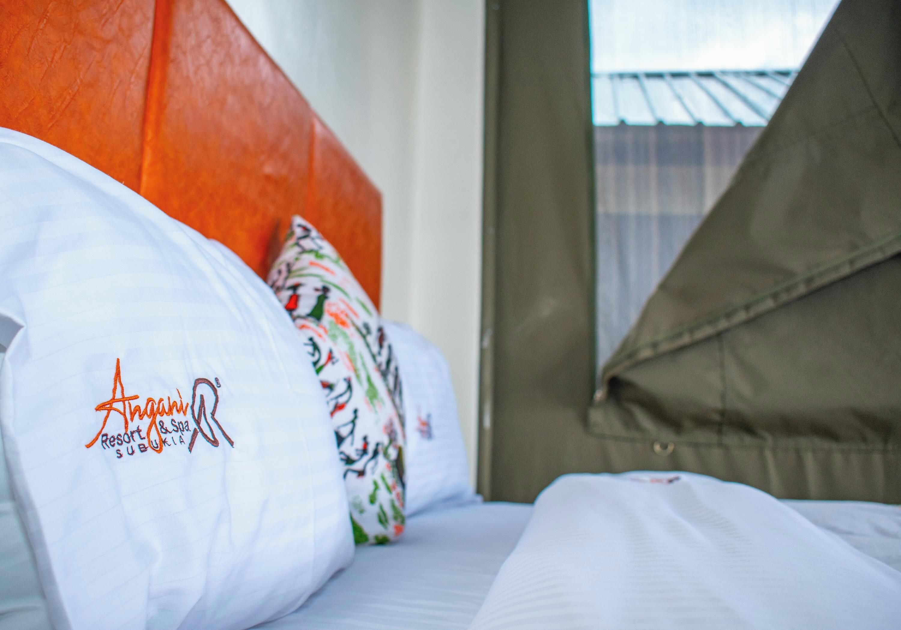 A hotel room with a bed, pillows, and a window with a view of a building.