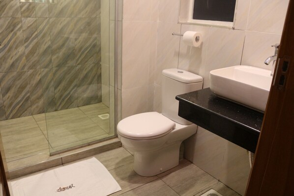 A bathroom with a toilet, sink, and shower area.