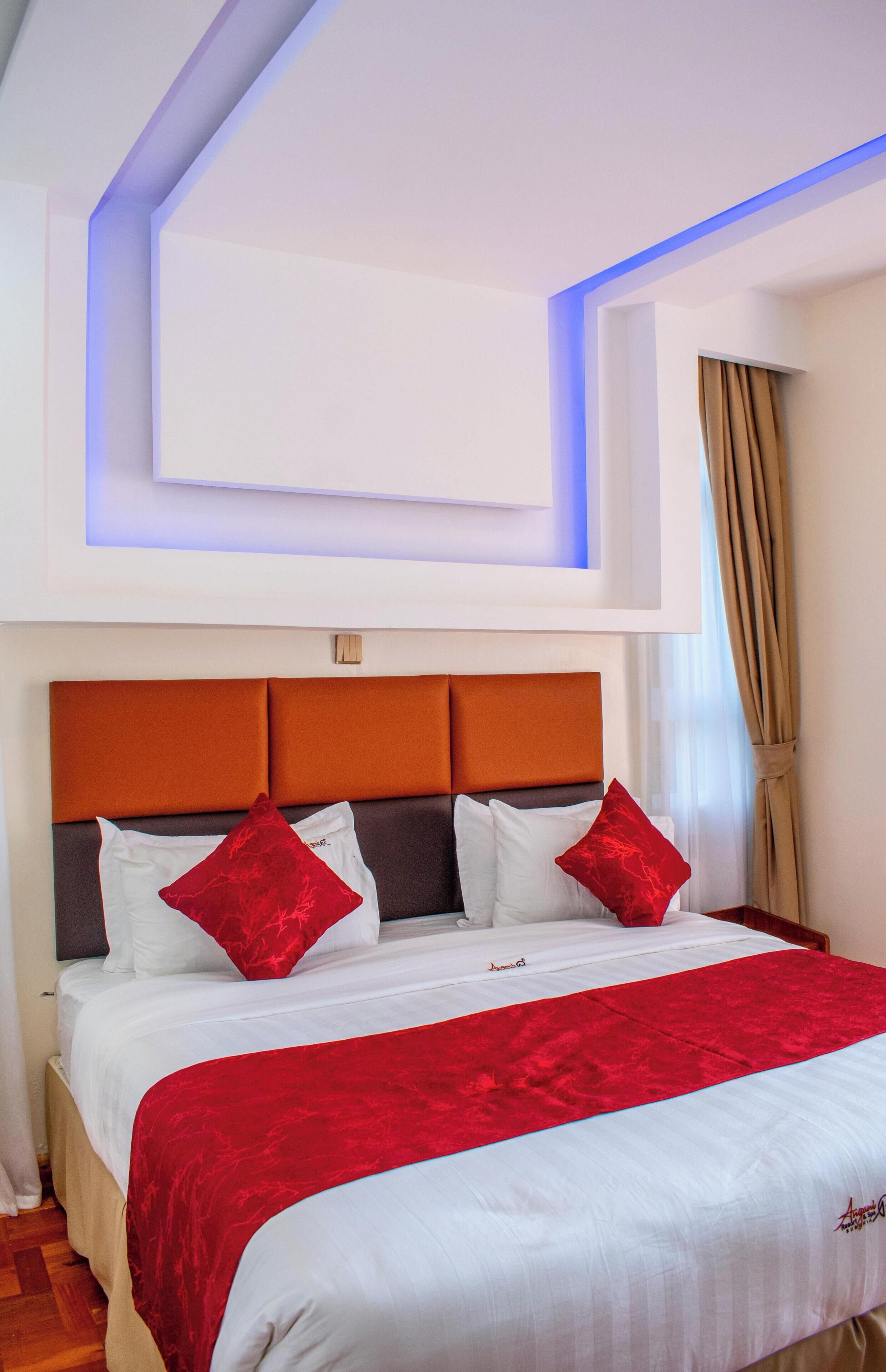 A hotel room with a large bed, a modern headboard, and a ceiling light fixture.