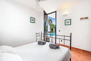 A bedroom with a bed, a chair, and a view of an outdoor swimming pool. - ANANA Binisafua (Sant Lluis)