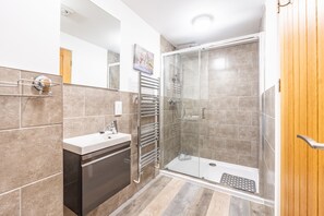 Une salle de bain moderne dotée d’une douche à parois de verre, d’un lavabo intégré et d’un porte-serviettes.
