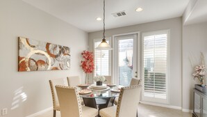 A dining area with a glass table, four chairs, a hanging light fixture, and a painting on the wall. - 2 Mi to Empire Polo Club: Indio Home w/ Fireplace! (Indio)
