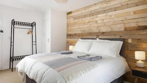 A bedroom with a wooden headboard, a bed with white bedding, a black metal ladder, and bedside lamps. - Beautiful Historic High Street Cottage in Burford (Burford)