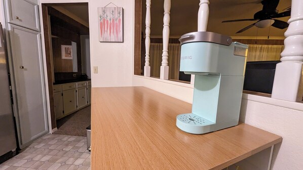 A kitchen with a light blue coffee maker on a wooden countertop, a white refrigerator, and a window with curtains. - Charming retro home. Minutes from downtown and ERAU. Pet friendly. (Prescott)