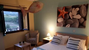 A hotel room with a bed, a chair, a small table, a nightstand with a lamp, and a window with a view of the outdoors. - Panmar Villa 5 minutes from Saint Nicholas beach (Zakynthos)