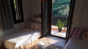 A bedroom with two beds, a balcony with a potted plant, and a view of greenery outside. - Panmar Villa 5 minutes from Saint Nicholas beach (Zakynthos)