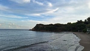 A beach with a sandy shore and a rocky outcrop in the distance. - Panmar Villa 5 minutes from Saint Nicholas beach (Zakynthos)