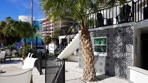 Un edificio moderno con una escalera, asientos exteriores y una palmera.