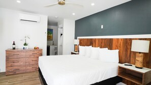 Una habitación de hotel moderna con una cama grande, mesitas de noche de madera, un aparador y un ventilador de techo.