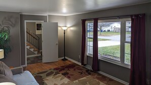 A living room with a sofa, a lamp, a patterned rug, and a view of the outside. - Pinball House | Pet-Friendly | Quiet Neighborhood (Columbus)