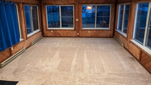A spacious room with wooden walls, large windows, and a ceiling fan. - Pinball House | Pet-Friendly | Quiet Neighborhood (Columbus)