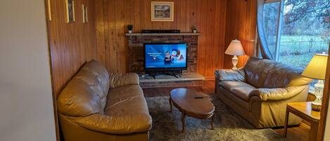 A cozy living room with a fireplace, leather sofas, and a television.