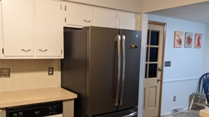 A kitchen with white cabinets, a stainless steel refrigerator, and a dishwasher. - Pinball House | Pet-Friendly | Quiet Neighborhood (Columbus)