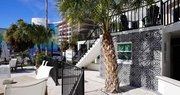 Un edificio moderno con una escalera, asientos exteriores y una palmera.