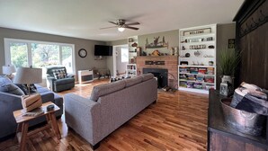 Ein Wohnzimmer mit Kamin, einer Couch, einem Fernseher und einem Bücherregal.