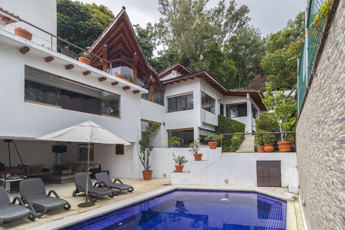 A modern house with a swimming pool, outdoor seating, and potted plants.
