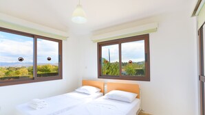 A bedroom with two beds, large windows, and a view of greenery. - 4 Bedroom Villa, Private Pool, Latchi, Cyprus (Latchi)