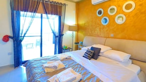 A hotel room with a bed, towels, a nightstand, a lamp, and a window with curtains. - 3 Bedroom Villa, Private Pool, 250m to Latchi Beach (Latchi)