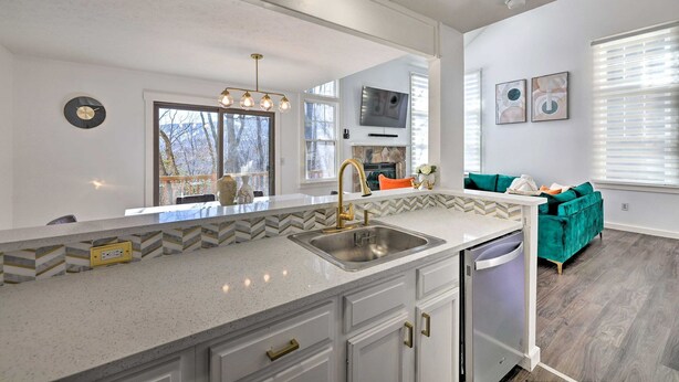 A modern kitchen with a large island, a built-in dishwasher, and a dining area with a teal sofa. - Brand New Modern-Chic Townhome with Deck! (Tannersville)