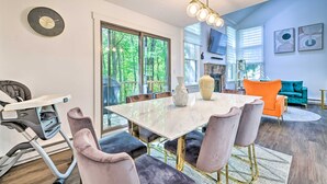 A modern living room with a large white table, plush chairs, a teal sofa, and a fireplace. - Brand New Modern-Chic Townhome with Deck! (Tannersville)
