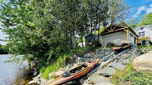 Een vakantiehuis aan het meer, met kajaks en een steiger.