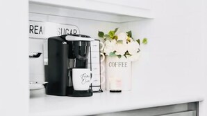 Une cuisine équipée d’une machine à café, d’un récipient à sucre et d’un vase décoré sur le thème du café.