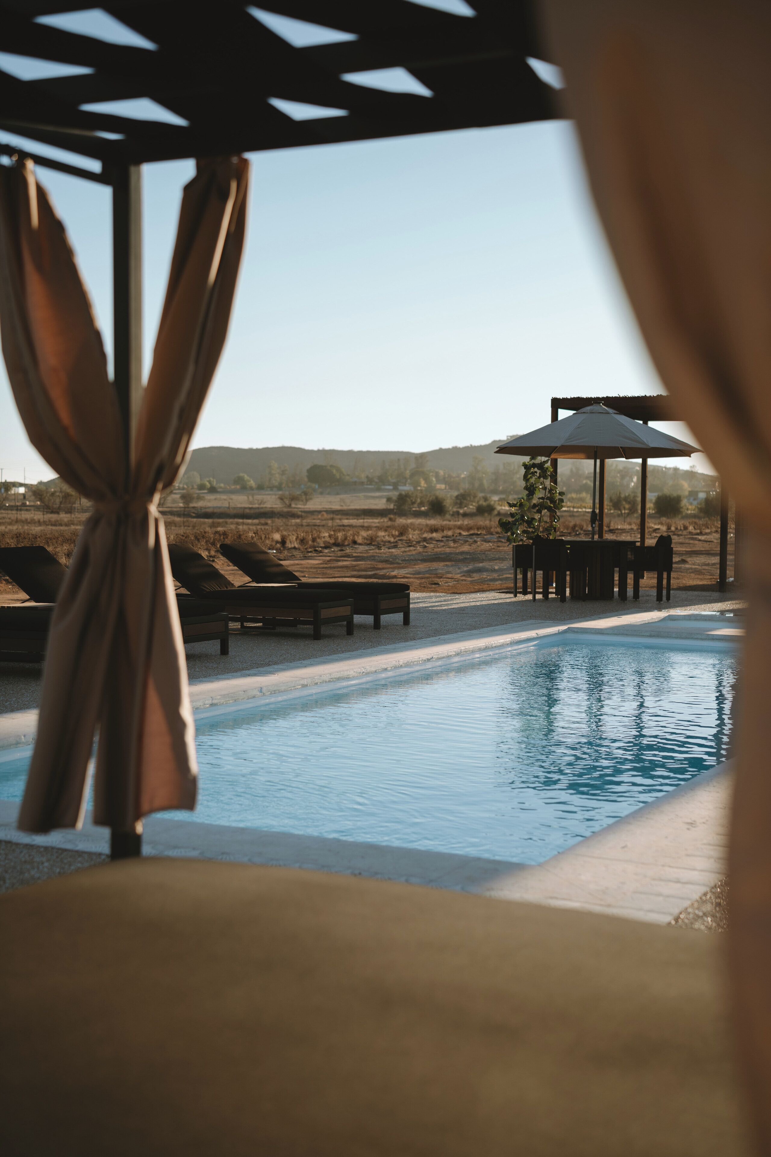 A pool area with lounge chairs and a gazebo.