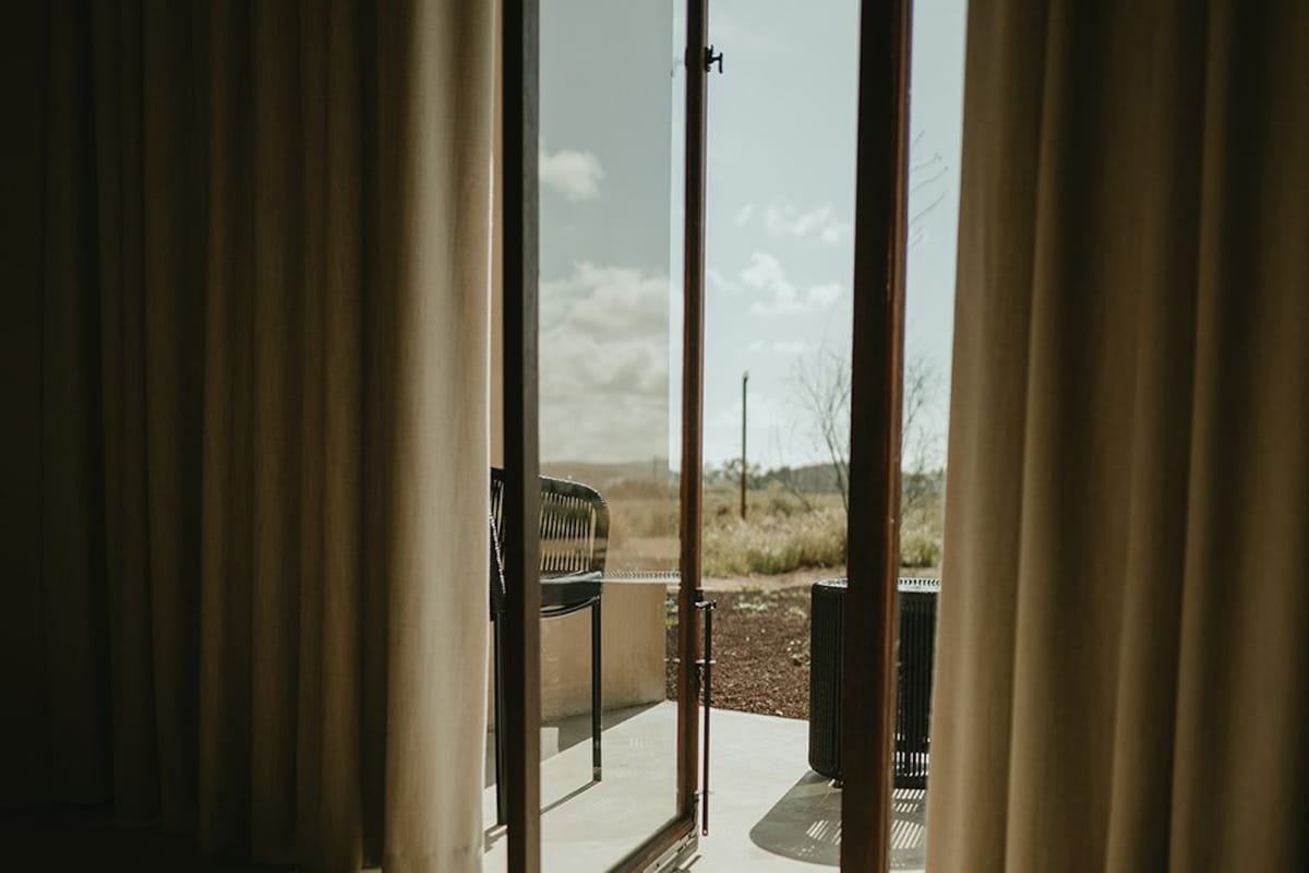 A room with a sliding glass door leading to an outdoor patio with a bench and a trash can.