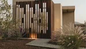A modern building with a minimalist design, featuring a series of vertical wooden slats and a concrete facade. - EQU Hotel Boutique (Valle de Guadalupe)