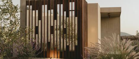 A modern building with a minimalist design, featuring a series of vertical wooden slats and a concrete facade.
