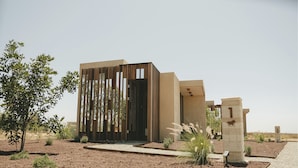 A modern building with a minimalist design, featuring a series of vertical wooden slats and a concrete base. - EQU Hotel Boutique (Valle de Guadalupe)