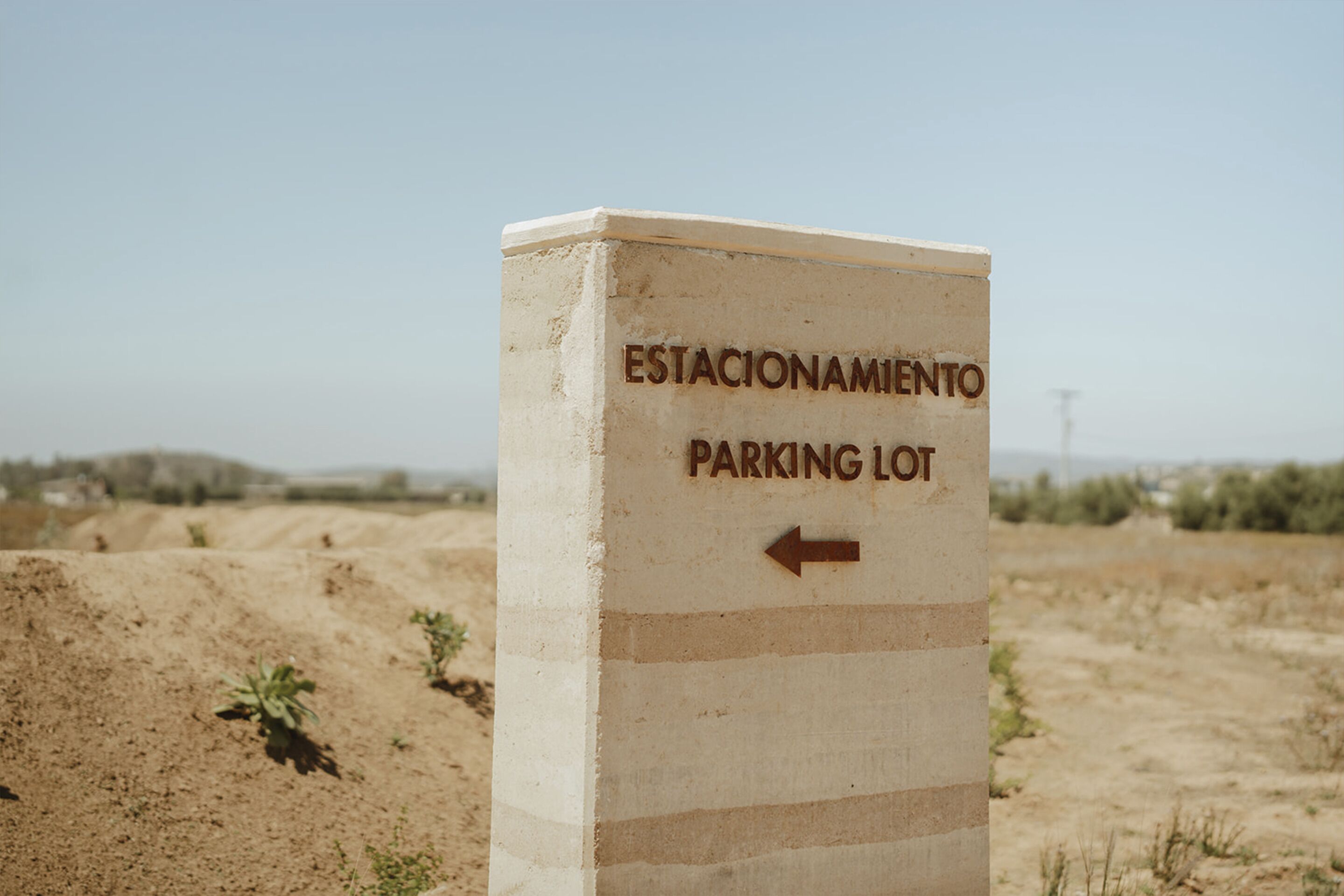 A sign for a parking lot with an arrow pointing to the left.