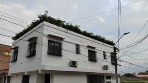 A two-story building with a flat roof, multiple windows with metal bars, and air conditioning units. - Amazing Apartment With Jacuzzi and City Views! (Cali)