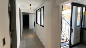 A corridor with tiled flooring, white walls, and a ceiling light fixture. - Amazing Apartment With Jacuzzi and City Views! (Cali)
