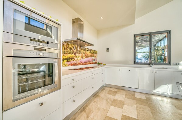 A modern kitchen with built-in appliances, a large window, and a decorative backsplash. - Finca with pool Villa Laiar in Mallorca (Sencelles)