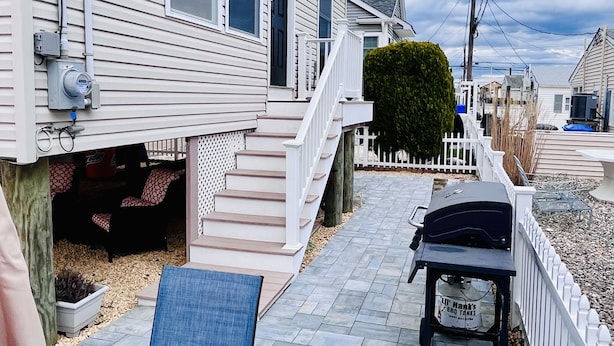 A residential area with a house featuring a covered patio with outdoor furniture, a small deck, and a sign advertising 'Lil' Mack's BBQ Tacos'. - Fun shore bungalow that is walkable to the beach!  (Lavallette)