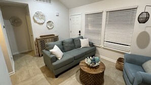 A living room with a grey sofa, a round wooden coffee table, and a blue armchair. - Fun shore bungalow that is walkable to the beach!  (Lavallette)