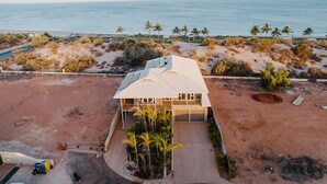 A beachfront property with a large house, a driveway, and a sandy beach.