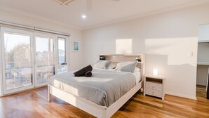 A bedroom with a bed, a nightstand, a window with a view, and a ceiling fan.