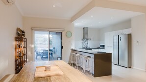 A modern kitchen with a central island, bar stools, and a refrigerator.