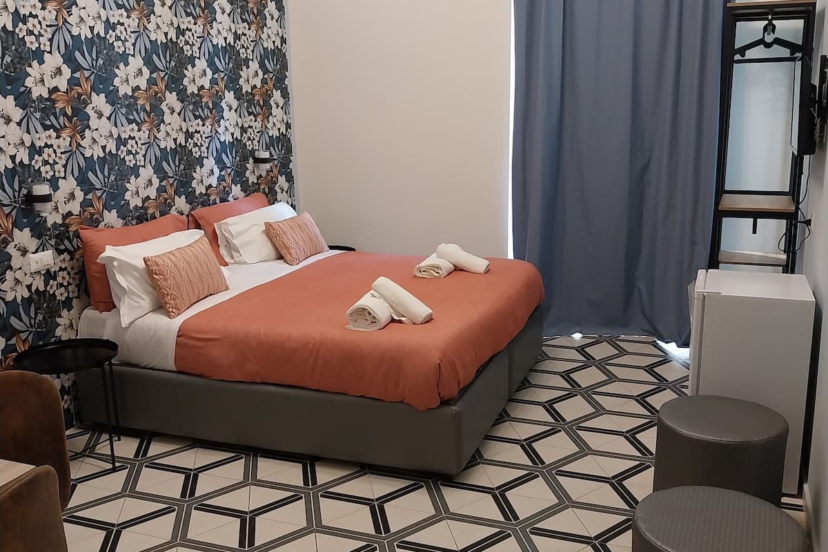 Ein Hotelzimmer mit Bett, Tisch, Stuhl, Kleiderschrank und Spiegel.