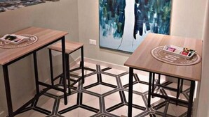 Una cocina moderna con un cuadro abstracto grande, dos mesas de madera y un suelo de baldosas geométricas.