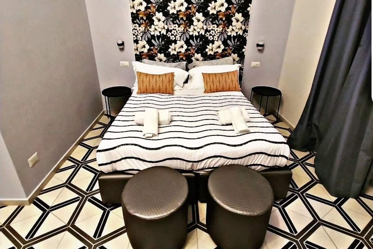 Ein Hotelzimmer mit einem Bett, zwei Nachttischen, einem Kopfteil mit floralem Muster und einem Boden mit geometrischem Muster.