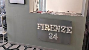 Un mostrador de recepción con un cuadro enmarcado encima, un adorno y un cartel que dice "FIRENZE 24".
