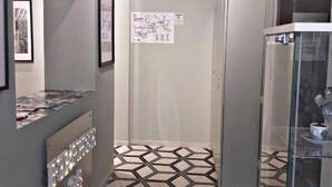Un pasillo con suelo de diseño geométrico, un refrigerador y una vitrina de vidrio.